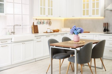Photo of Dining table, chairs and floral decor in kitchen. Interior design