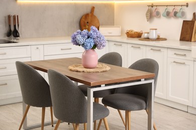 Photo of Dining table, chairs and floral decor in kitchen. Interior design