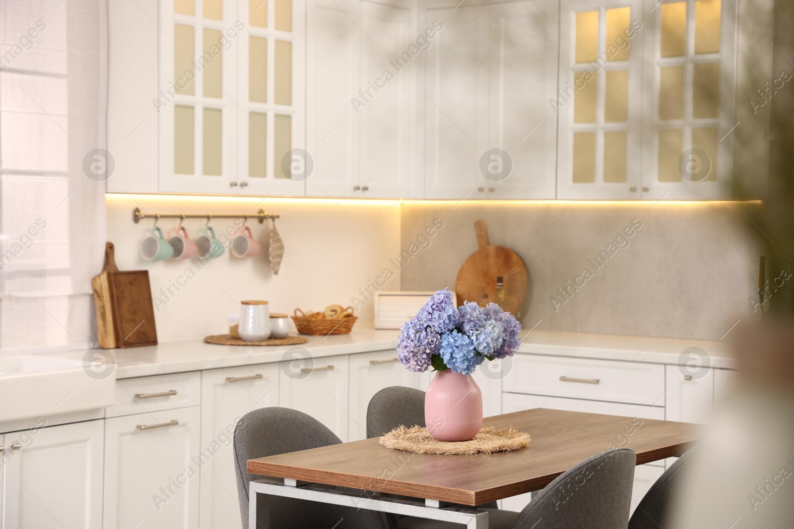 Dining table, chairs and floral decor in kitchen. Interior design Photo of Dining table, chairs and floral decor in kitchen. Interior design
