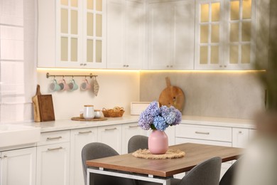 Photo of Dining table, chairs and floral decor in kitchen. Interior design