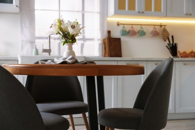 Photo of Dining table, chairs and floral decor in kitchen. Interior design