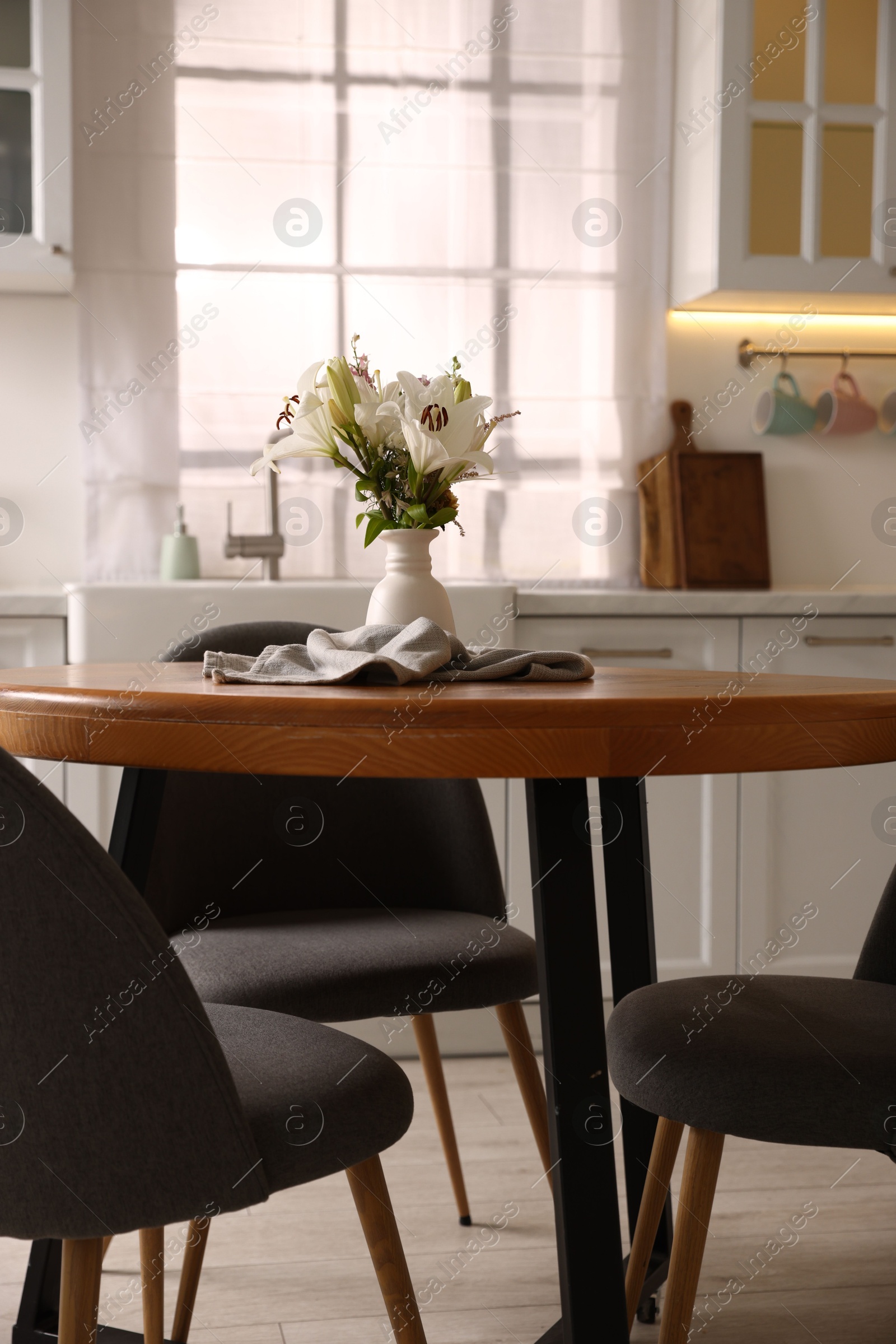 Photo of Dining table, chairs and floral decor in kitchen. Interior design