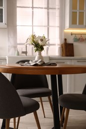Photo of Dining table, chairs and floral decor in kitchen. Interior design