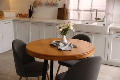 Photo of Dining table, chairs and floral decor in kitchen. Interior design