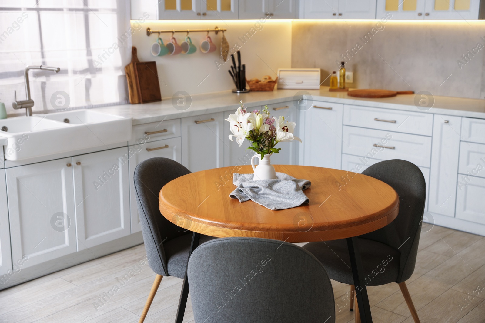 Photo of Dining table, chairs and floral decor in kitchen. Interior design
