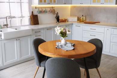 Photo of Dining table, chairs and floral decor in kitchen. Interior design