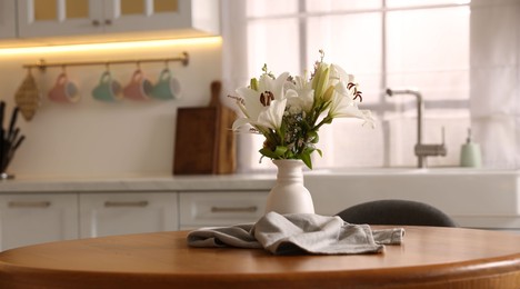 Photo of Vase with beautiful flowers on dining table in kitchen
