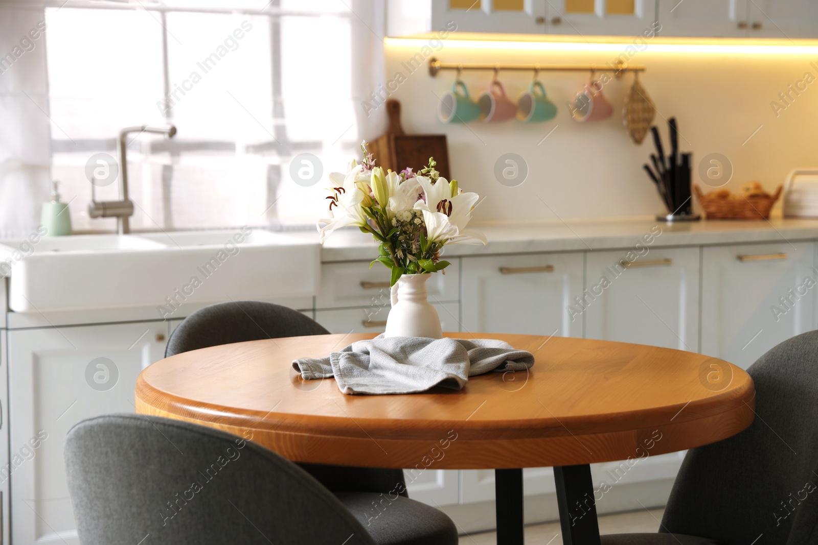 Photo of Dining table, chairs and floral decor in kitchen. Interior design