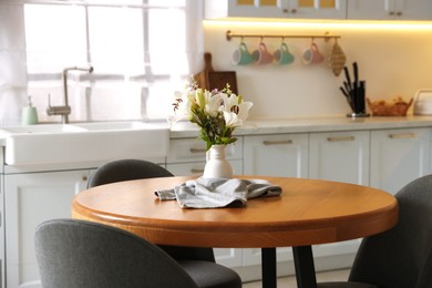 Photo of Dining table, chairs and floral decor in kitchen. Interior design