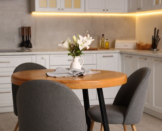 Photo of Dining table, chairs and floral decor in kitchen. Interior design