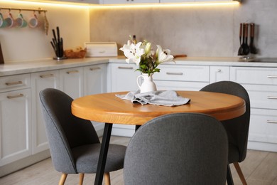 Photo of Dining table, chairs and floral decor in kitchen. Interior design