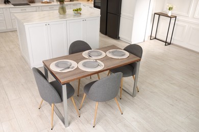 Photo of Kitchen interior with dining table, place setting and grey chairs