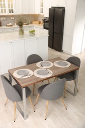 Photo of Kitchen interior with dining table, place setting and grey chairs