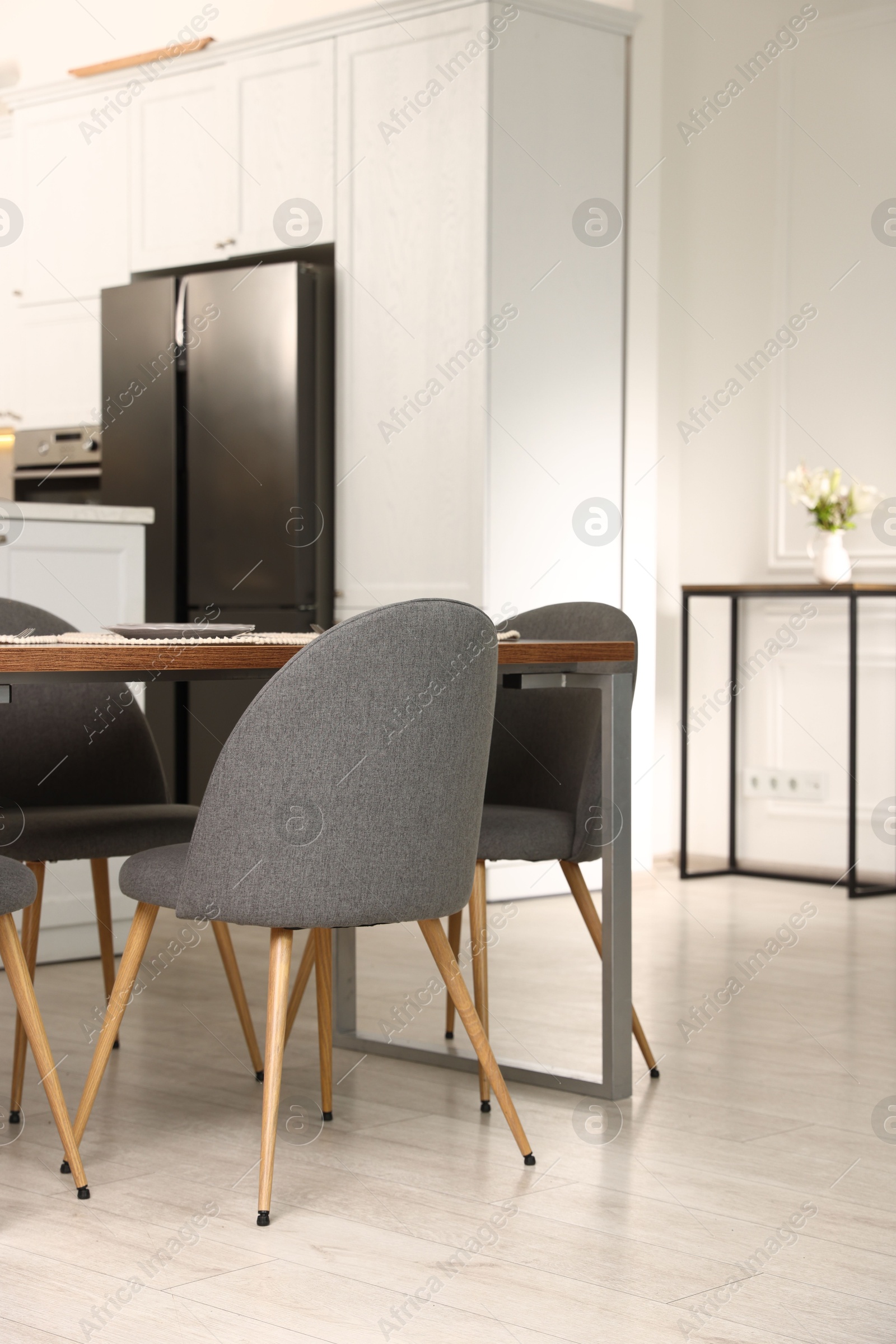 Kitchen interior with dining table, place setting and grey chairs Photo of Kitchen interior with dining table, place setting and grey chairs