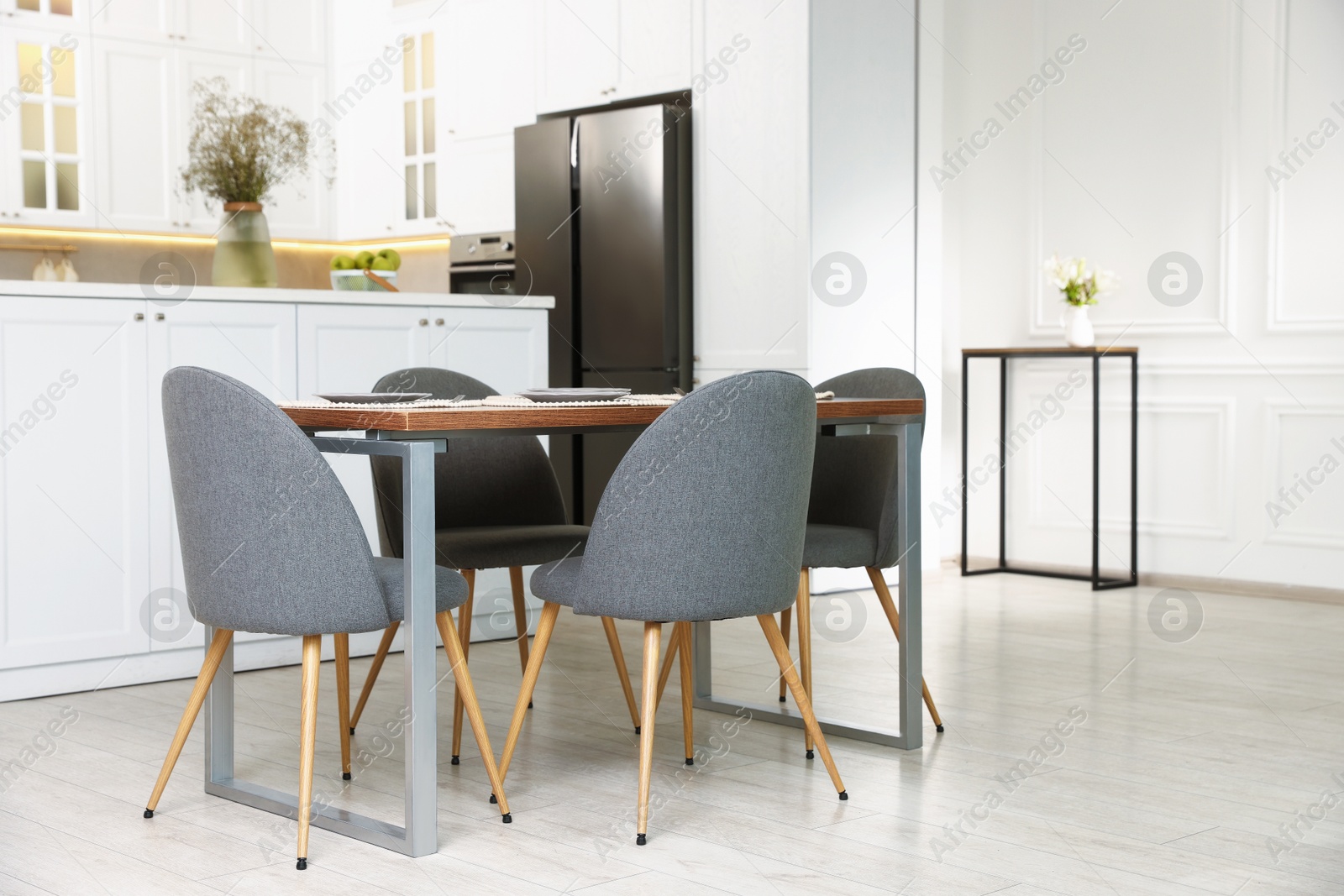 Kitchen interior with dining table, place setting and grey chairs Photo of Kitchen interior with dining table, place setting and grey chairs