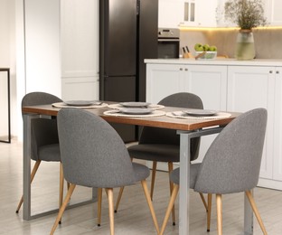Photo of Kitchen interior with dining table, place setting and grey chairs