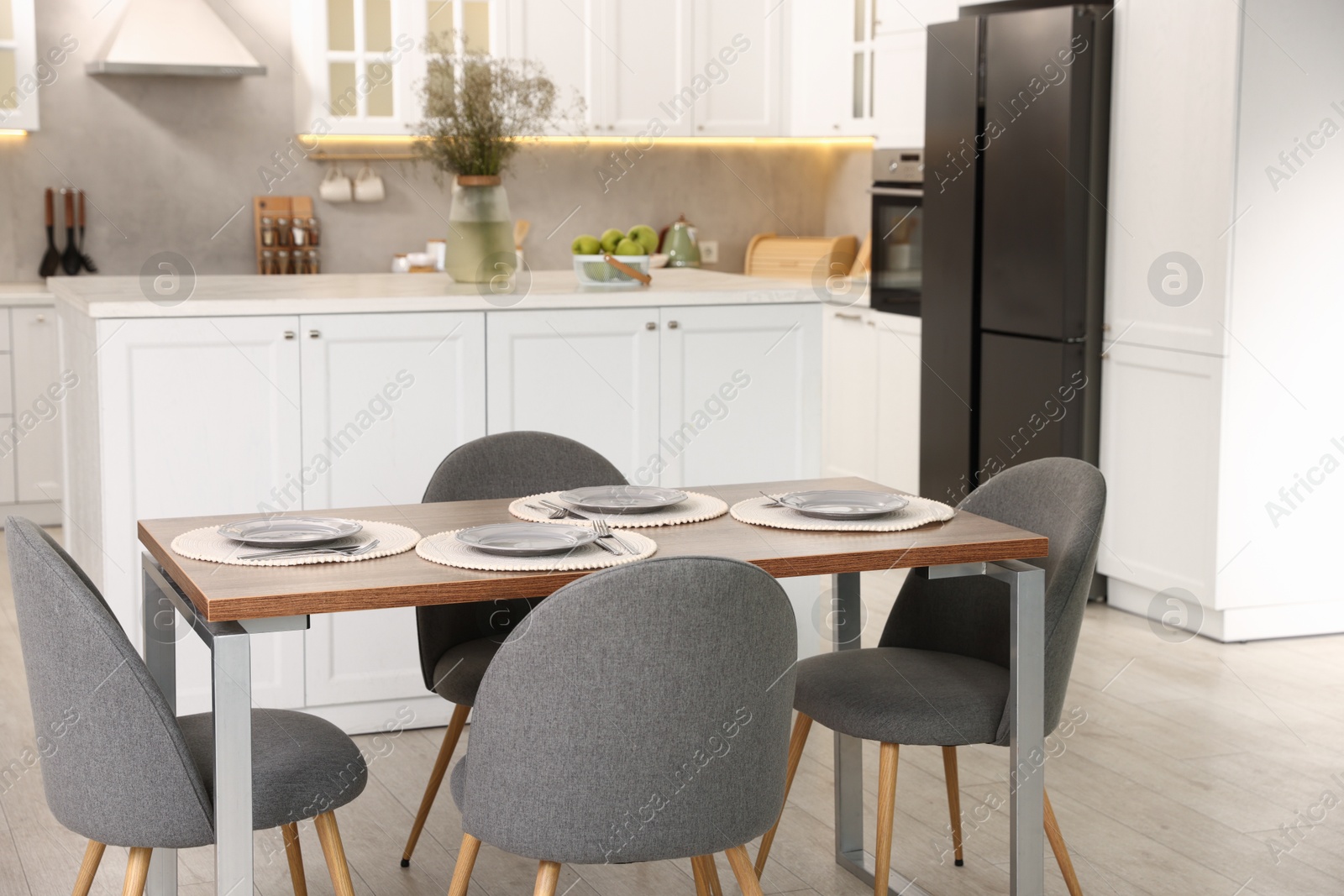 Kitchen interior with dining table, place setting and grey chairs Photo of Kitchen interior with dining table, place setting and grey chairs