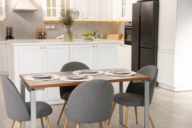 Photo of Kitchen interior with dining table, place setting and grey chairs