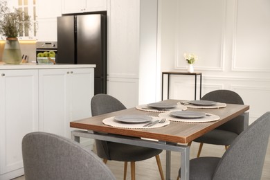Photo of Kitchen interior with dining table, place setting and grey chairs