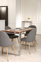 Photo of Kitchen interior with dining table, place setting and grey chairs