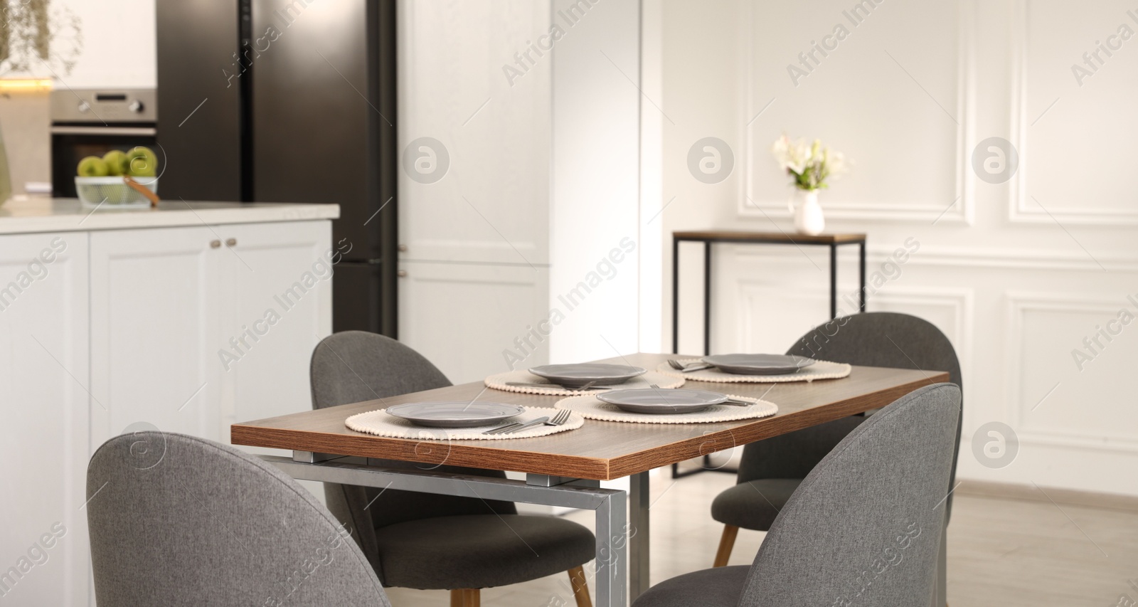 Photo of Kitchen interior with dining table, place setting and grey chairs