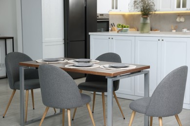 Photo of Kitchen interior with dining table, place setting and grey chairs