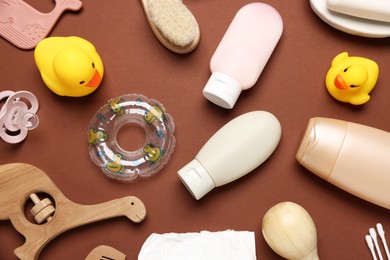 Photo of Baby bath accessories, cosmetic products and toys on brown background, flat lay