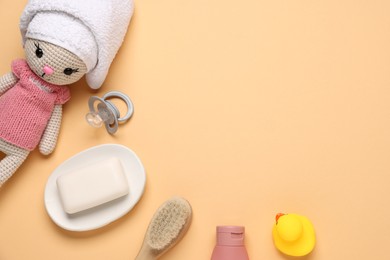 Photo of Baby bath accessories, pacifier and toy on pale orange background, flat lay. Space for text