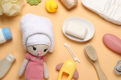 Photo of Baby bath accessories, care products and toys on pale orange background, flat lay