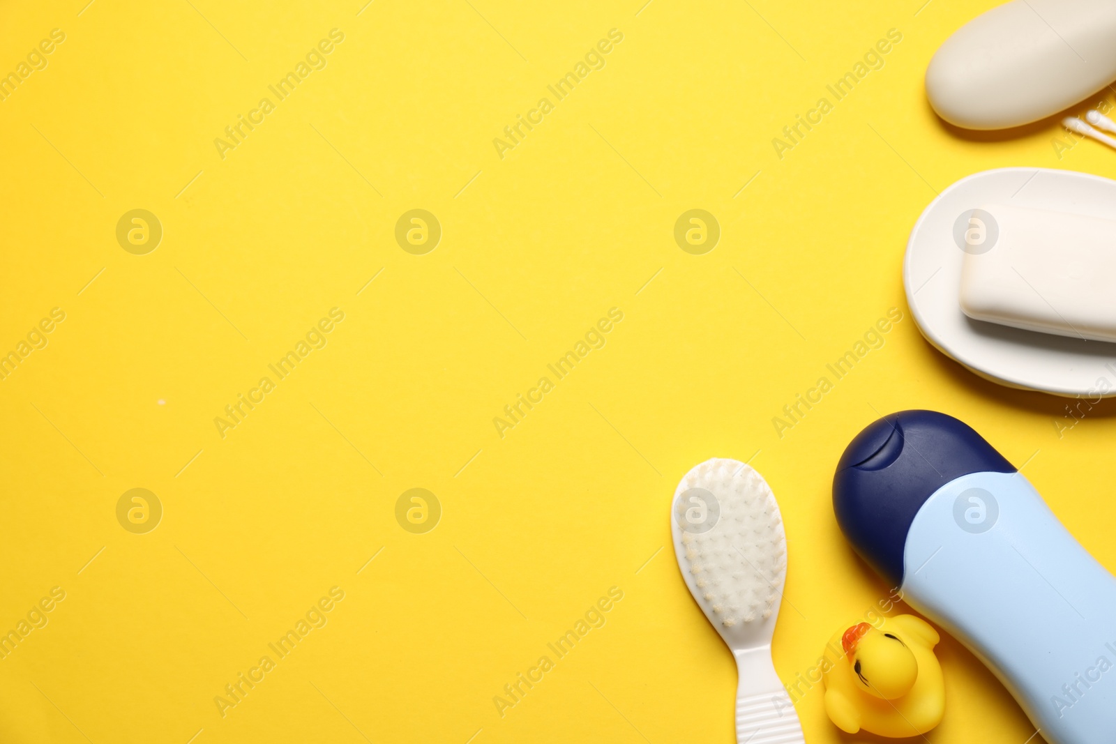 Photo of Baby bath accessories and cosmetic products on yellow background, flat lay. Space for text