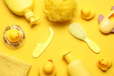 Photo of Baby bath accessories and care products on yellow background, flat lay