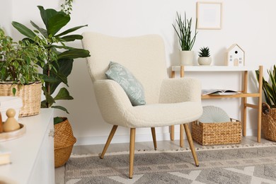 Photo of Stylish armchair with cushion in room. Interior design