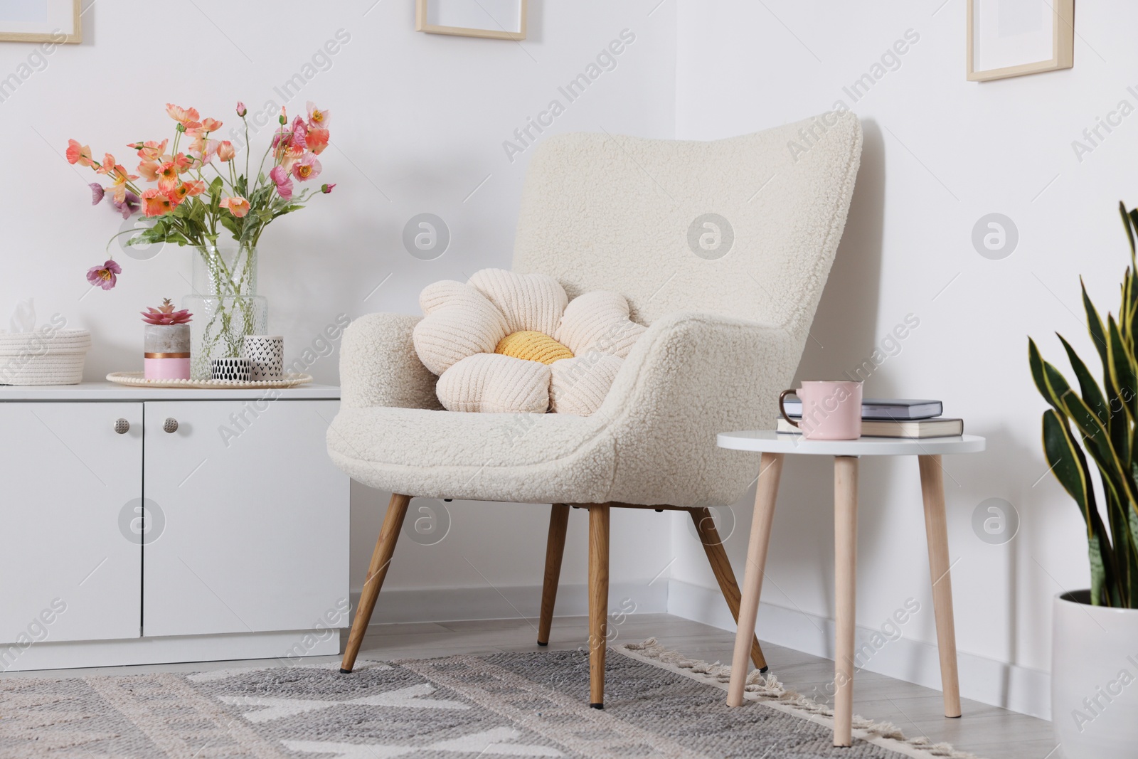 Photo of Stylish armchair with cushion in room. Interior design