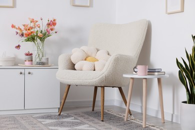 Photo of Stylish armchair with cushion in room. Interior design