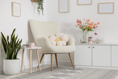 Photo of Stylish armchair with cushion in room. Interior design