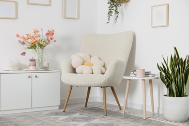 Photo of Stylish armchair with cushion in room. Interior design