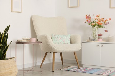 Photo of Stylish armchair with cushion in room. Interior design