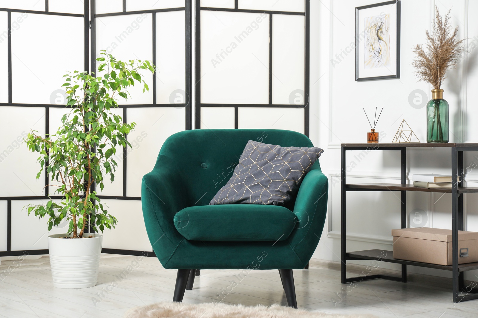Photo of Stylish armchair with pillow, console table and decor indoors. Interior design