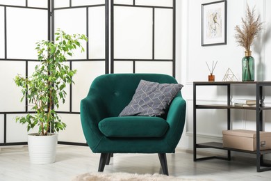 Photo of Stylish armchair with pillow, console table and decor indoors. Interior design
