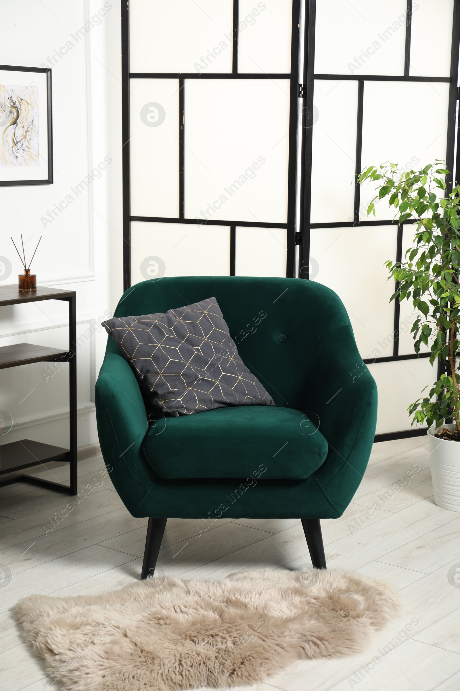 Photo of Stylish armchair with pillow, console table and houseplant indoors. Interior design