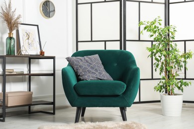 Photo of Stylish armchair with pillow, console table and decor indoors. Interior design