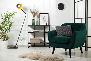 Photo of Stylish armchair with pillow, console table and decor indoors. Interior design