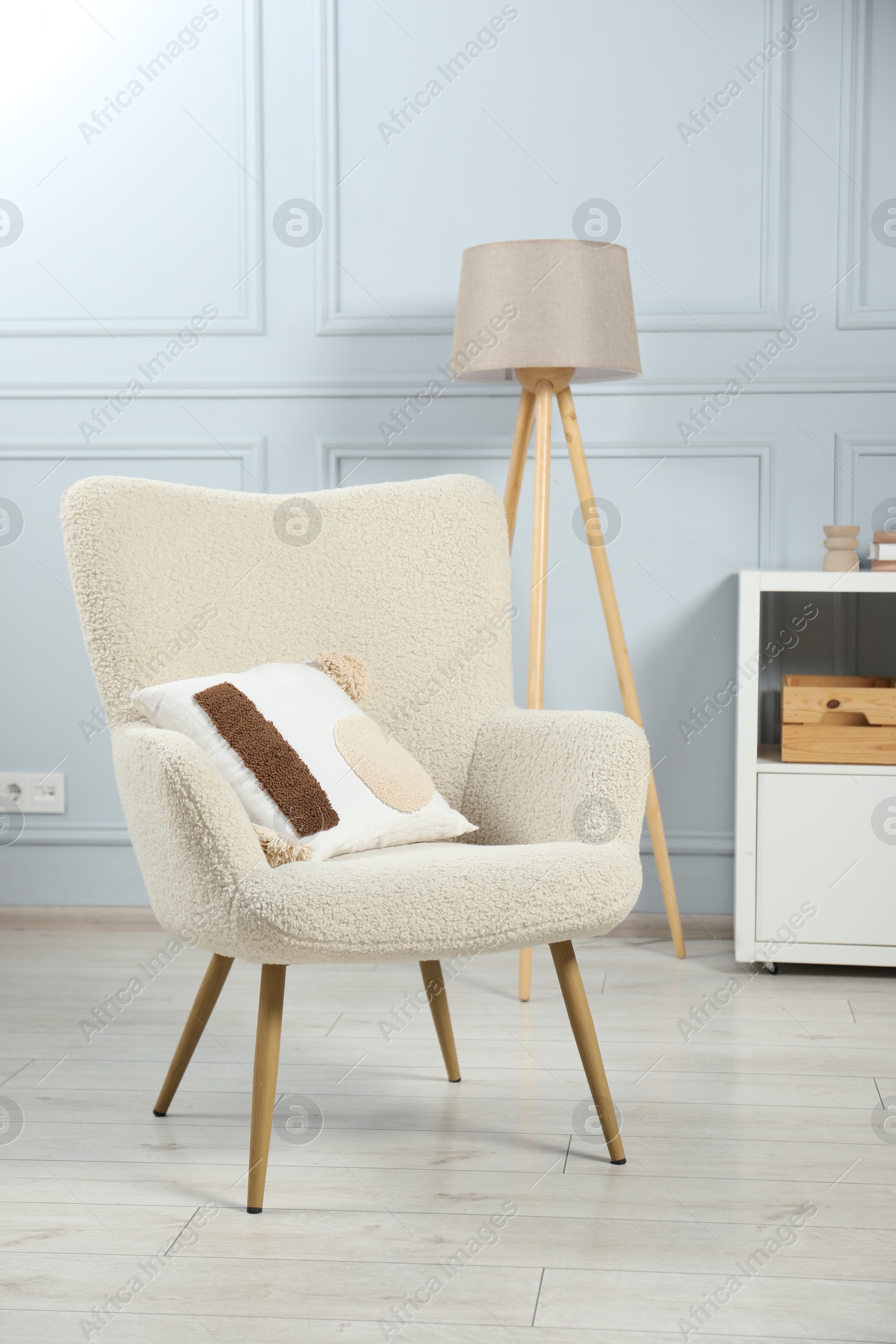 Photo of Stylish armchair with pillow and lamp indoors. Interior design