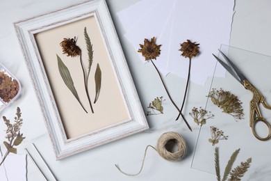 Photo of Flat lay composition with dry flowers and picture frame on white marble table
