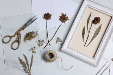 Photo of Flat lay composition with dry flowers and picture frame on white marble table