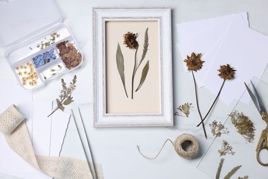 Photo of Flat lay composition with dry flowers and picture frame on white marble table
