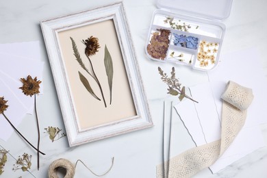 Photo of Flat lay composition with dry flowers and picture frame on white marble table