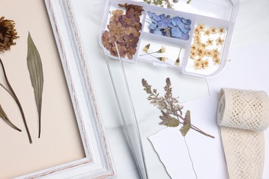 Photo of Flat lay composition with dry flowers and picture frame on white marble table