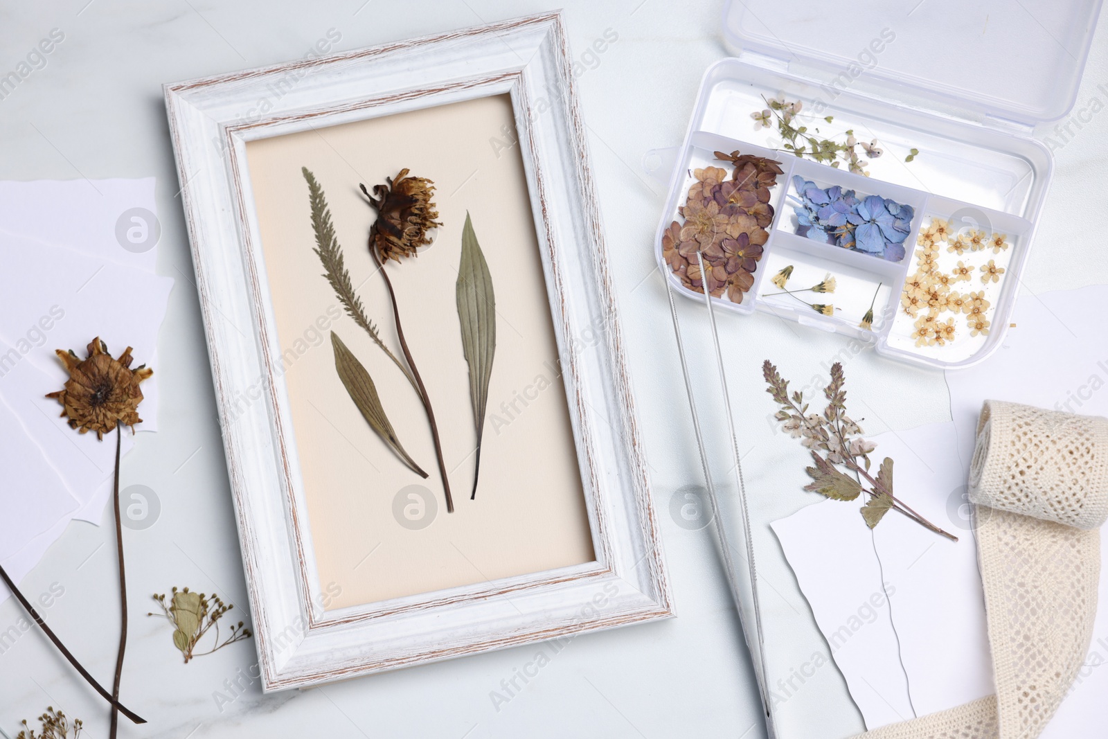 Photo of Flat lay composition with dry flowers and picture frame on white marble table