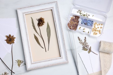 Photo of Flat lay composition with dry flowers and picture frame on white marble table